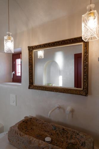 a bathroom with a large mirror and a sink at The Architect's Cave House in Oia