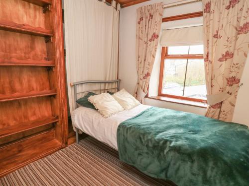 a small bedroom with a bed and a window at Brook Cottage in Llanidloes