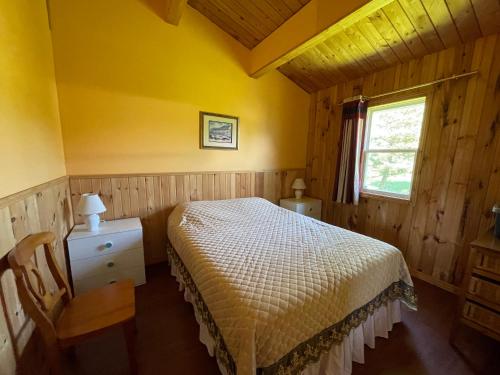 un dormitorio con una cama y una ventana en Beach & Breeze Cottages, en Stanley Bridge