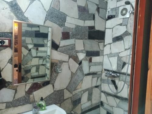 a bathroom with a stone wall with a sink and a mirror at Guest House Bake in Gjirokastër