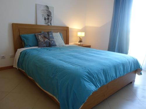 een slaapkamer met een groot bed met een blauwe deken bij Gloria Maris Cabanas Gardens in Cabanas de Tavira