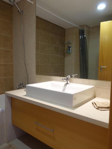 een badkamer met een witte wastafel en een spiegel bij Gloria Maris Cabanas Gardens in Cabanas de Tavira