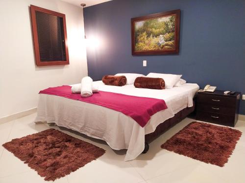 a bedroom with a large bed with two rugs on it at Hotel Karlo By GHO Hoteles in Cali