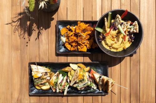 three plates of food on a wooden table at Sol House The Studio - Calviá Beach - Adults Only in Magaluf