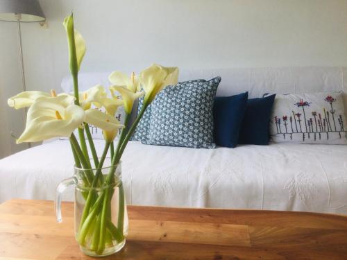 a vase with yellow flowers on a table next to a couch at Victoria's Summerhouse in Andros