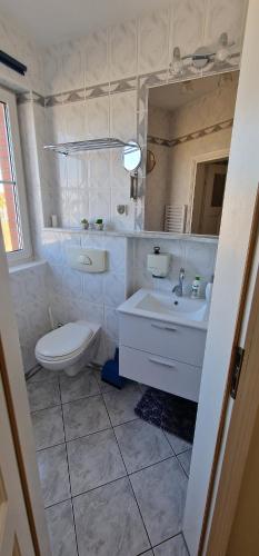 a white bathroom with a toilet and a sink at Apartamenty Hexagon 7 in Grzybowo