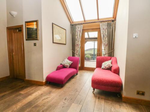 a living room with two chairs and a window at Rough Bank Barn in Rochdale