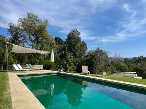 a swimming pool with two lawn chairs and a umbrella at Slope Design Villa - Architecture villa with private pool in Ponte de Lima