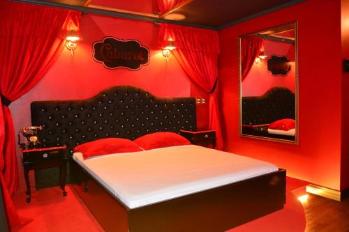 um quarto vermelho com uma cama e um espelho em Amore Mio (Adult Only) em Gramado