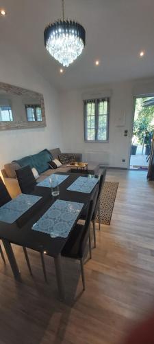 - un salon avec une table, des chaises et un lustre dans l'établissement Gîte le jardin d eau, à Lamothe-Montravel