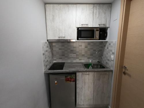 a small kitchen with a sink and a microwave at MEMORIA in Corfu Town