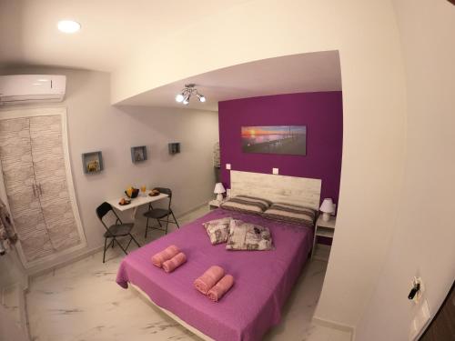 1 dormitorio con cama morada y mesa en MEMORIA, en Corfú