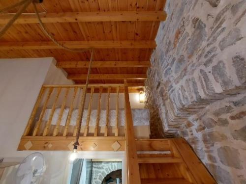 a wooden staircase in a room with a stone wall at Ήλιος Πατσακης in Symi