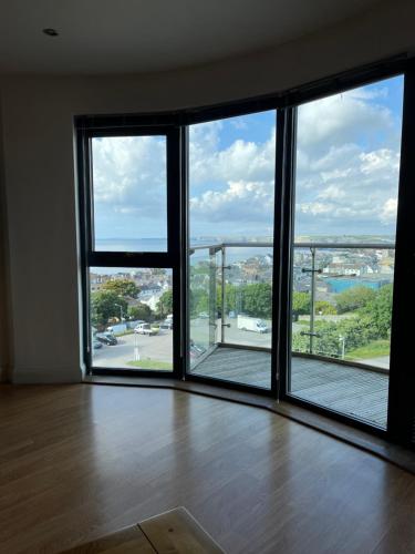 an empty room with large windows with a view of a city at Newquay Horizons in Newquay