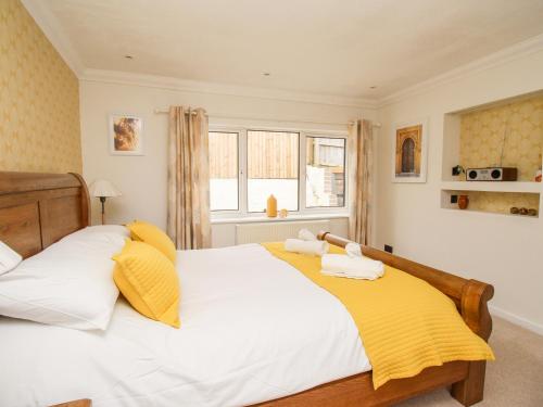 a bedroom with a bed with white and yellow pillows at White Cottage in Bere Regis