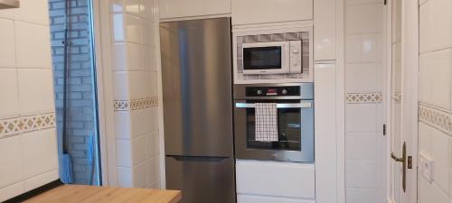 cocina con nevera de acero inoxidable y microondas en Valdenoja-Sardinero Apartment Suite Beach, en Santander