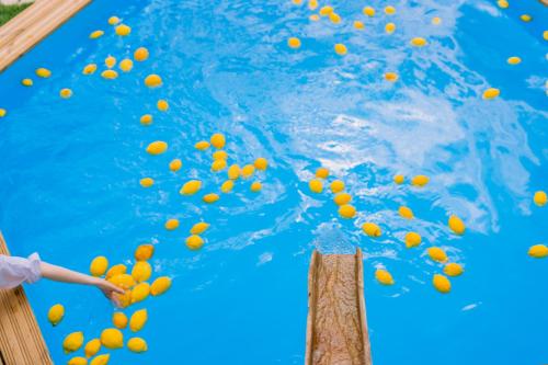a person throwing orange balls into a swimming pool at Villa Le Murelle in Tramonti