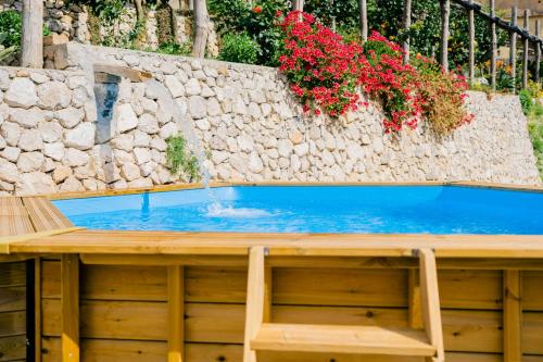 a pool of water with a stone wall and flowers at Villa Le Murelle in Tramonti