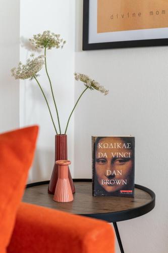 a table with a vase and a book and a orange chair at Sea view Pine house in Makry Gialos