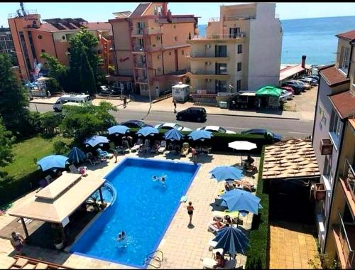 a swimming pool with umbrellas and people sitting around it at Sunny House Family in Nesebar