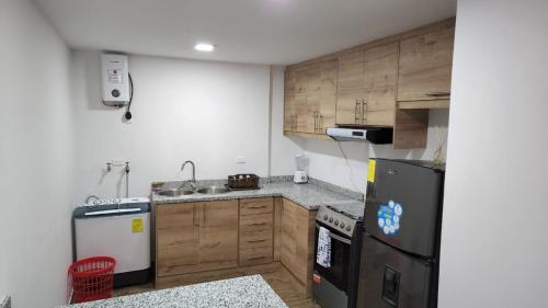a kitchen with wooden cabinets and a black refrigerator at Departamento completo de dos habitaciones la Estación del Tren 3 in Riobamba