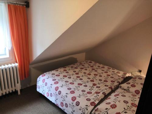 a bedroom with a bed with a floral bedspread and a window at Hostel Pestalozza in Špindlerův Mlýn
