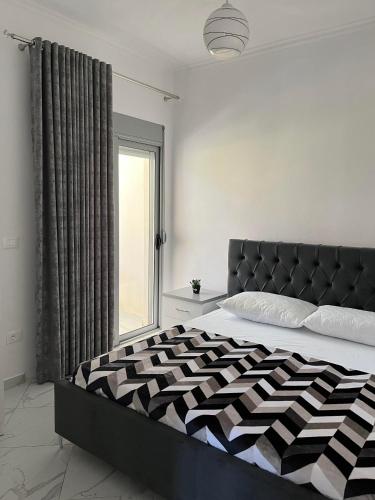 a bedroom with a black and white bed with a window at Xhefri's Apartments in Vlorë