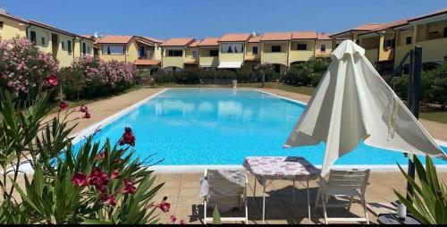 a swimming pool with an umbrella and a table and chairs at Appartement Baia delle mimose H9 in Sassari
