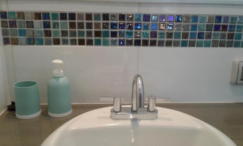 a sink with a faucet and a bottle of soap at NEREO rooms in Lima