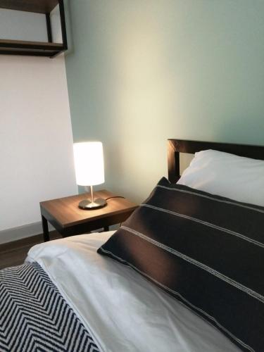 a bedroom with a bed with a lamp on a table at NEREO rooms in Lima