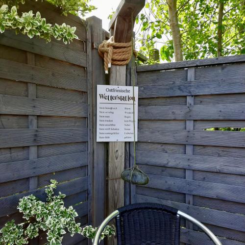 a sign on a fence with a chair next to it at Gästehaus Mia in Norddeich