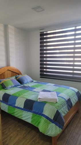 a bedroom with a bed with a blue and green comforter at Departamentos La Estación del tren de dos habitaciones in Riobamba