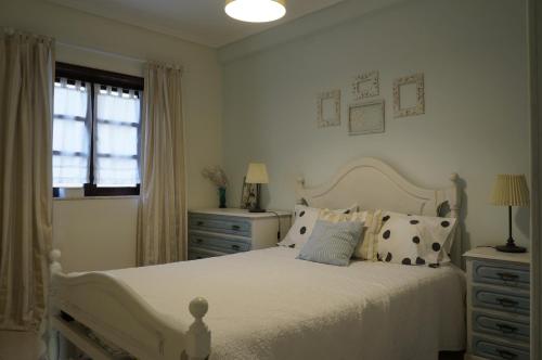 um quarto com uma cama branca com almofadas e uma janela em Beach Front Apartment em Gafanha da Nazaré