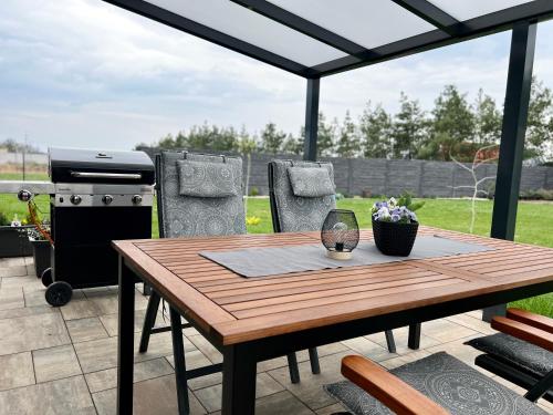 a patio with a wooden table and a grill at Apartmány DOME in Doksy