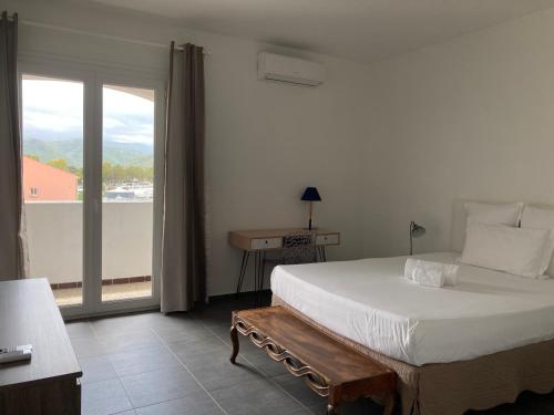 a bedroom with a large bed and a large window at Soleil Corse in Saint-Florent