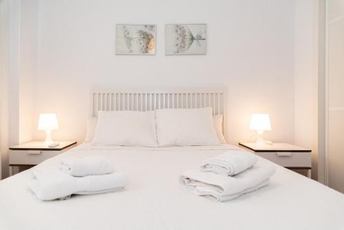 Un dormitorio con una cama blanca con toallas. en Like Home Sevilla - Museo, en Sevilla