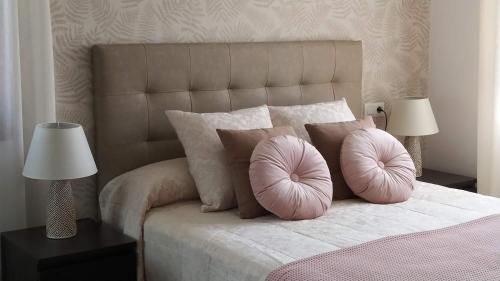 1 cama con 2 almohadas rosas y 2 lámparas en FINCA LA GRANDA DE LA CONCHA en Nueva de Llanes