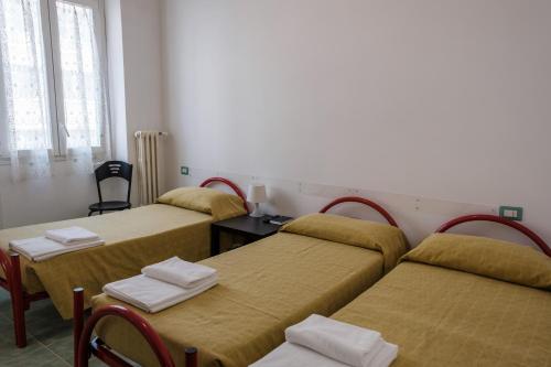 a room with three beds and a table and chairs at Foresteria Roma Esercito della Salvezza in Rome
