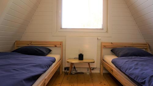 two beds in a small room with a window at Domek Mały Las in Rzyki