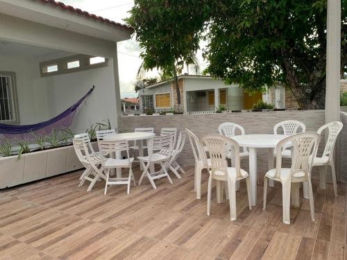 a patio with white tables and chairs on a deck at casa de 4 quartos perto do Forte Orange Itamaracá in Itamaracá