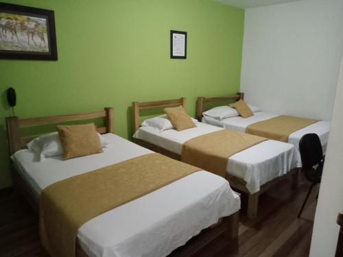 3 camas en una habitación con paredes verdes en Hotel Cañaveral Plaza, en Manizales