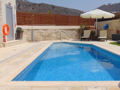 a swimming pool with blue water in front of a house at Charalambos Holiday Cottage in Kalavasos