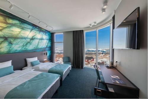 a hotel room with two beds and a desk at Best Western Plus Hotel Ilulissat in Ilulissat