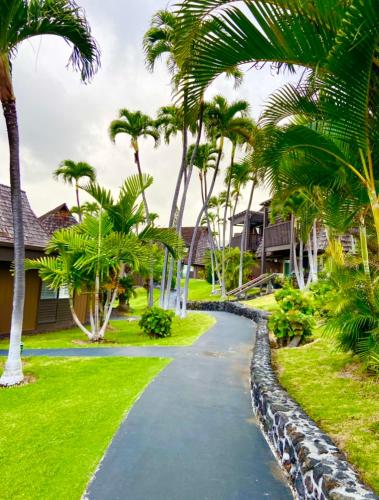 a walkway in front of a house with palm trees at Beachfront 1 Bedroom Condo with Private Beach, Pool, Hot Tub in Pahala