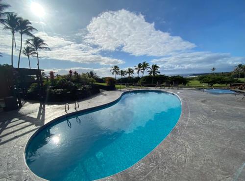 a large blue swimming pool with palm trees in the background at Beachfront 1 Bedroom Condo with Private Beach, Pool, Hot Tub in Pahala