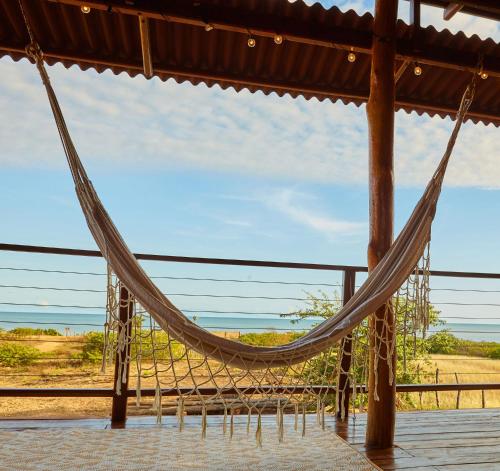 a hammock on a deck with a view of the beach at Corazon Guajiro Cabaña frente a Playa Solitaria en Dibulla cerca a Palomino - Cabin in front of Solitary Beachs in Dibulla