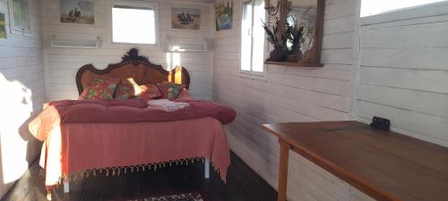 a bedroom with a bed with a red blanket at Los furgones de Areco in San Antonio de Areco