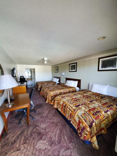 a hotel room with two beds and a desk at Deluxe Inn and Suites in Raymondville