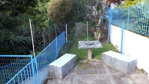a fence with a stone bench next to a gate at Casa Agradável com piscina. in Miguel Pereira