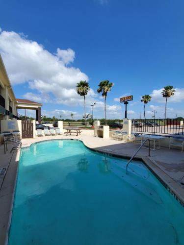 a swimming pool at a resort with palm trees at Deluxe Inn and Suites in Raymondville